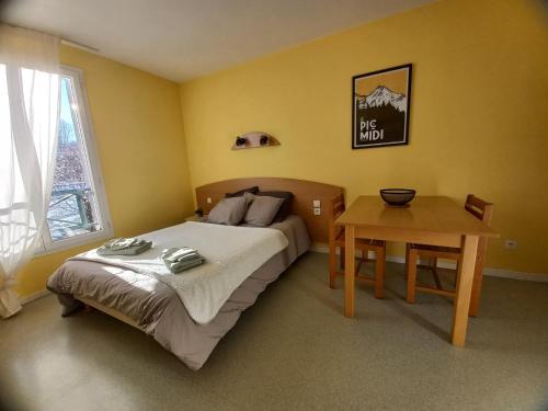 une petite chambre avec un lit et une table dans l'établissement Studio très bien situé, belle vue, parking privé, à Bagnères-de-Bigorre