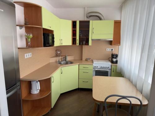 a small kitchen with green cabinets and a table at Lada Wings 2 in Narva