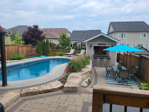 een zwembad met stoelen en een blauwe parasol bij Living the Dream with Inground Heated Pool, Hot Tub, & Beach in Cobourg