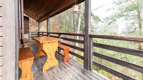 - une table et un banc en bois sur la terrasse couverte d'une cabine dans l'établissement Les Cochettes -166 - Chalet spacieux 8 pers, à Doucy