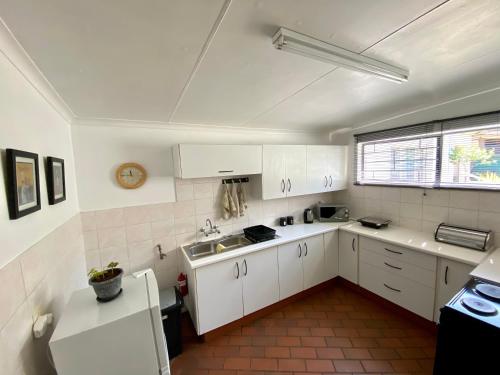 a kitchen with white cabinets and a sink at The White House in Hartbeespoort