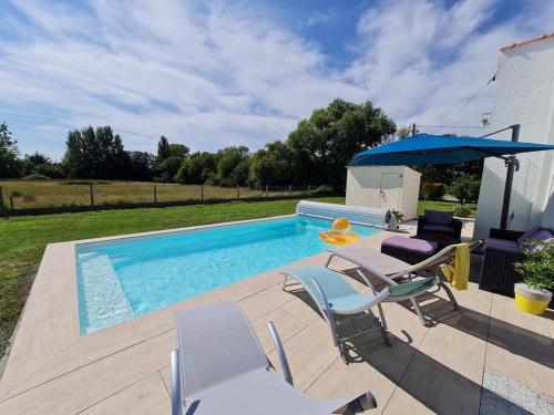 une piscine avec des chaises et un parasol dans l'établissement JOLIE MAISON AVEC PISCINE CHAUFFEE EN CAMPAGNE, au Perrier