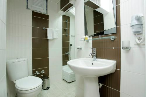 a white bathroom with a toilet and a sink at Taksim Istiklal Suites in Istanbul