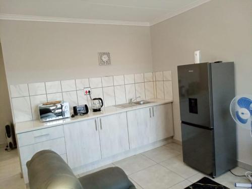 a kitchen with white cabinets and a stainless steel refrigerator at Bella's self contained daily accommodation in Meyerton