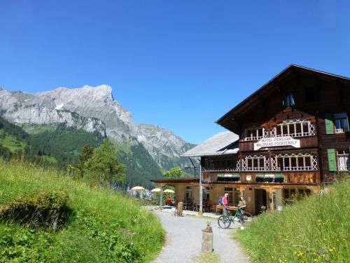 a large wooden building with a mountain in the background at Hotel Waldrand in Kiental
