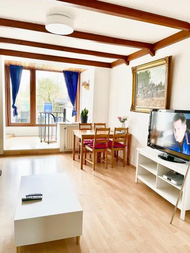 ein Wohnzimmer mit einem TV und einem Tisch in der Unterkunft Düsseldorf Messe, 2-bedroom Duplex Apartment with Terrace and Garden in Düsseldorf