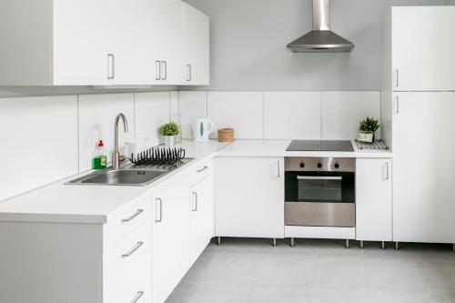 a white kitchen with white cabinets and a sink at Apartamenty Przy Plaży in Sopot