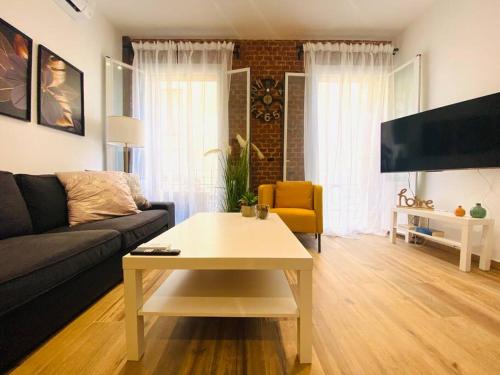 Style & Design Flat in the Center of Madrid في مدريد: غرفة معيشة مع أريكة وطاولة قهوة