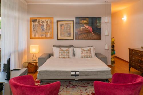 1 dormitorio con 1 cama y 2 sillas rosas en Trilocale Como Centro, Esclusivo 100 MQ con 3 Balconi, en Como