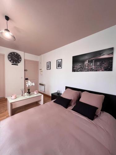een slaapkamer met een groot bed en een klok aan de muur bij Studio cosy proche du lac d'Enghien in Soisy-sous-Montmorency