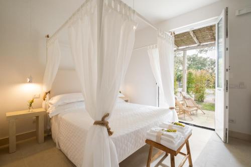 a bedroom with a white bed with a canopy at Masseria Rauccio in Torre dell'Orso