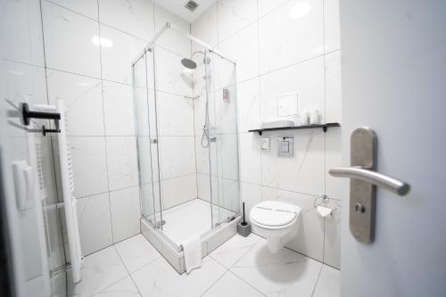 a white bathroom with a shower and a toilet at Hotel Zur alten Stadtkellerei Leipzig in Leipzig