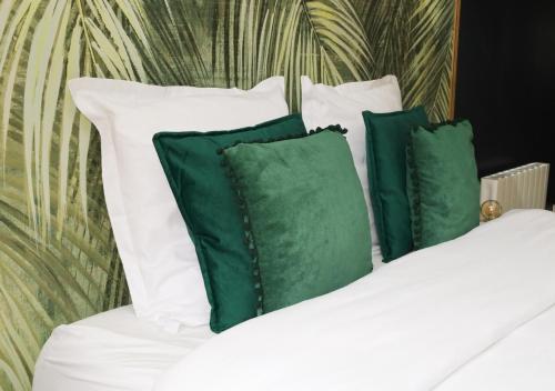 uma cama com almofadas brancas e almofadas verdes em L’Esmeralda Spa ancien garage devenu suite luxueuse em Évreux