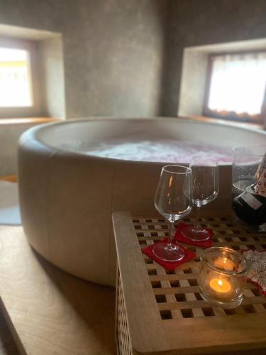 a bath tub with two wine glasses on a table at Residenza d'Epoca Albergo Grimani in Ampezzo