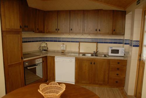 a kitchen with wooden cabinets and a table with a microwave at Casa da Moreia in Sabugueiro