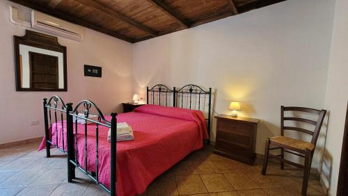 a bedroom with a bed with a red blanket and a chair at Residenza Le Orchidee in Galtellì