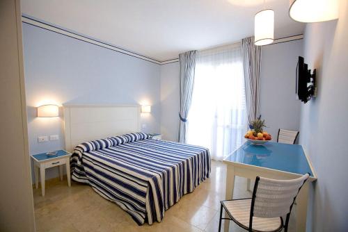a hotel room with a bed and a desk and a window at Resort Cala La Luna in Favignana