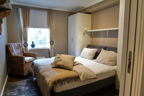 um quarto com uma cama, uma cadeira e uma janela em Victoriagården- Losji em Grimstad