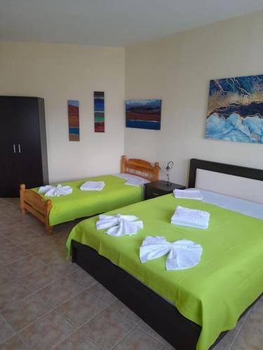 two beds in a room with green sheets and towels at SummerAndros Skalario in Andros