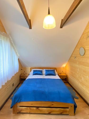 a bedroom with a blue bed in a attic at Roztocze - Domek - Trzy Sosny in Rebizanty
