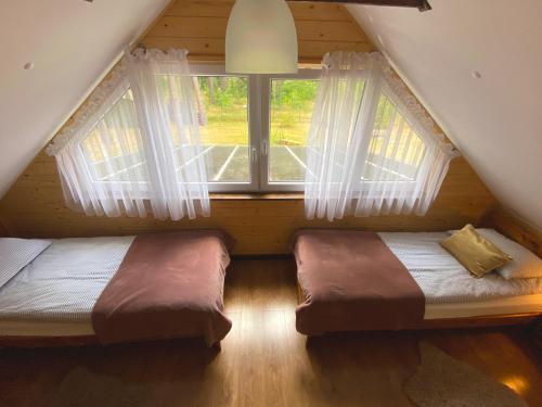 een slaapkamer op zolder met 2 bedden en een raam bij Roztocze - Domek - Trzy Sosny 
