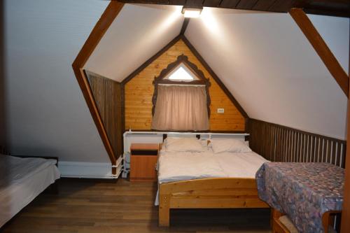 a attic bedroom with a bed and a window at Guest house Dvir Pysanka in Kosiv