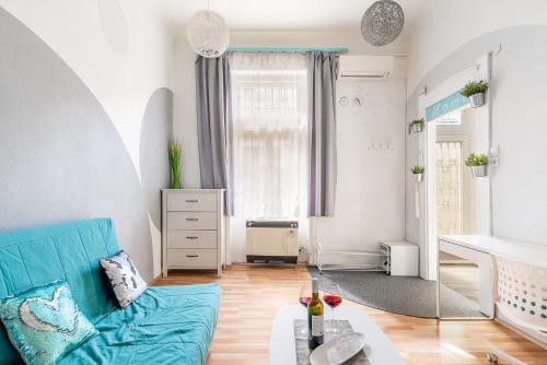 uma sala de estar com um sofá azul e uma mesa em Sunny Dots Apartment em Budapeste