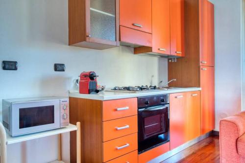 cocina con armarios de color naranja y microondas en CaseOspitali - Casa Niden il tuo nido a Cernusco vicino alla metro 2pax en Cernusco sul Naviglio