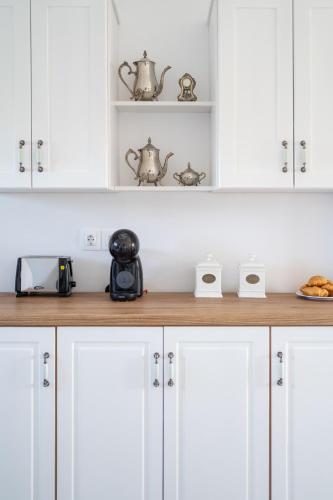 a kitchen counter with white cabinets and tea pots at Endless Blue in Xerokampos
