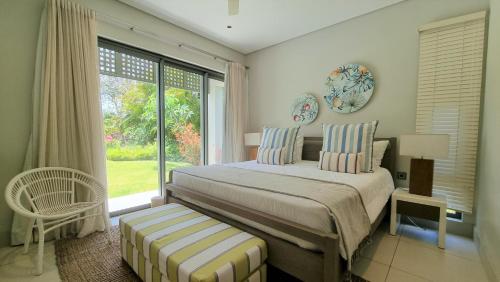 a bedroom with a bed and a large window at Superior 4-Bedroom Villa at Anahita Golf & Spa Resort's in Beau Champ