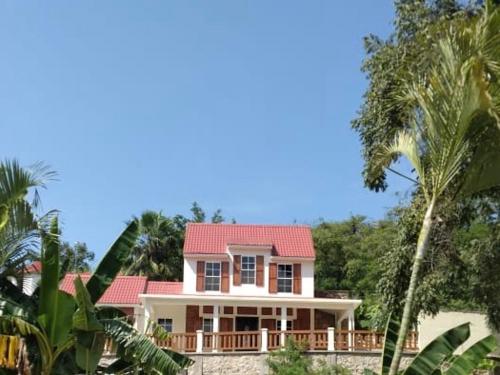 a house with a red roof and some palm trees at Casa la CEIBA in Tancama