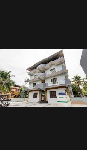 a large white building with palm trees in front of it at Parppidam Residency in Trippapur