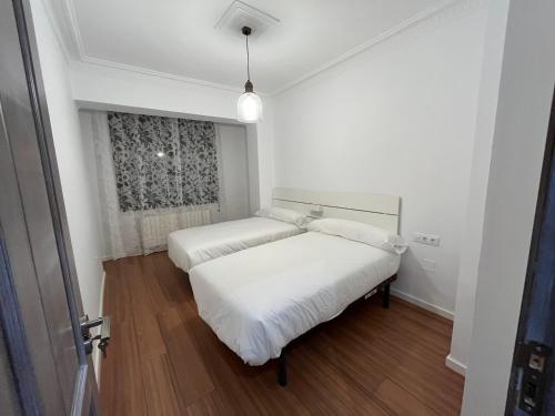 2 Betten in einem weißen Zimmer mit Fenster in der Unterkunft Casa Ferma in Teruel