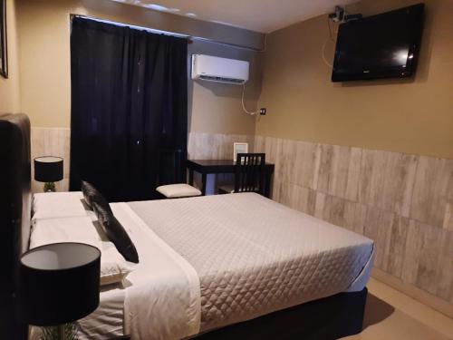 ein Schlafzimmer mit einem Bett und einem TV an der Wand in der Unterkunft Hotel La Terminal in San Miguel de Tucumán
