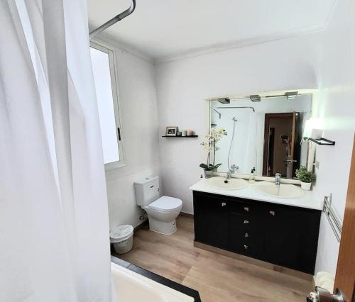 a bathroom with a sink and a toilet and a mirror at Apartamento céntrico y luminoso cerca de la playa. in Castellón de la Plana