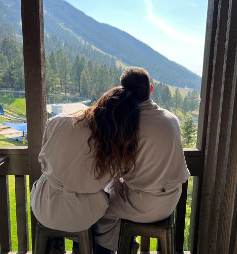 a man and woman sitting on a chair looking out a window at Snow King Resort in Jackson