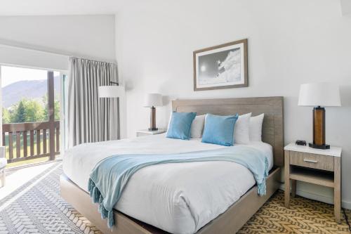 a bedroom with a bed with blue pillows and a balcony at Snow King Resort in Jackson