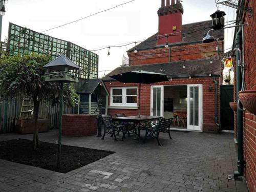 a patio with a table and chairs in front of a building at Station House-Hinton Admiral in Christchurch