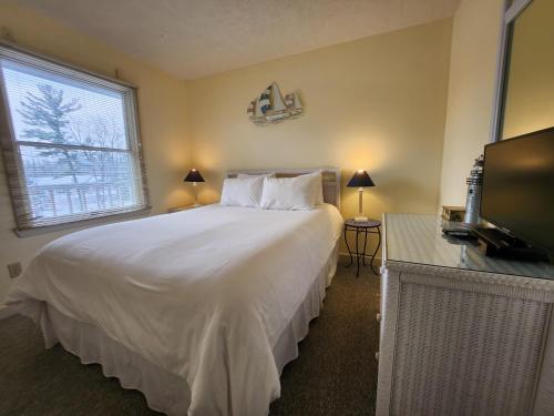 a bedroom with a large white bed and a television at North Shore Inn TC 306 in Traverse City