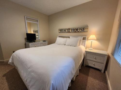 - une chambre avec un grand lit et un couvre-lit blanc dans l'établissement North Shore Inn TC 308, à Traverse City
