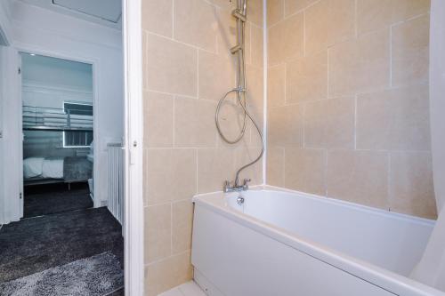 a bathroom with a white tub and a shower at NICE THREE BEDROOM HOUSE in Manchester in Manchester