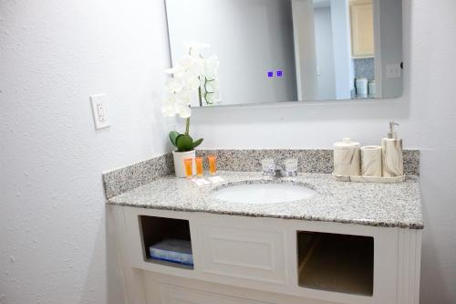 ein Bad mit einem Waschbecken und einem Spiegel in der Unterkunft Sun & Sand Resort Oceanfront Suites in Virginia Beach