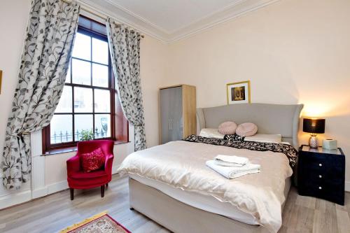 a bedroom with a large bed and a red chair at Inviting 9-Bed House in Aberdeen in Aberdeen