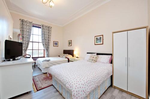 a bedroom with two beds and a flat screen tv at Grand Mansion 9 Beds Sleeps 17 Parking - Groups in Aberdeen