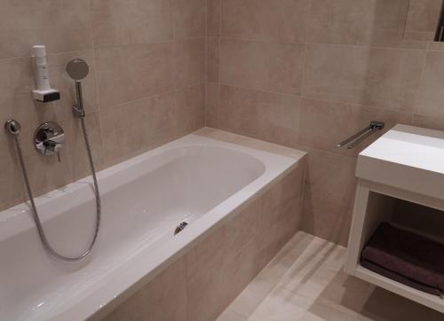 a bathroom with a bath tub and a sink at Wally Berg-Appartements in Zams