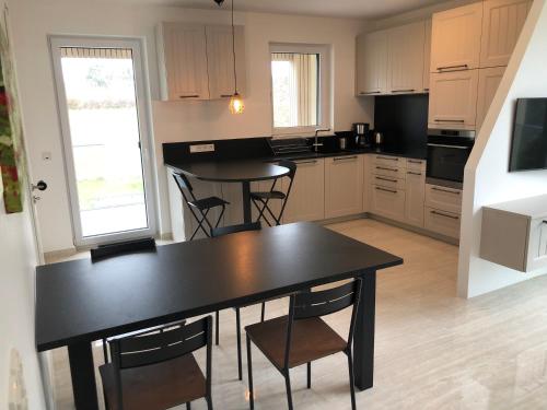 a kitchen with a black table and chairs in it at Résidence du Golf Eselborn in Eselborn
