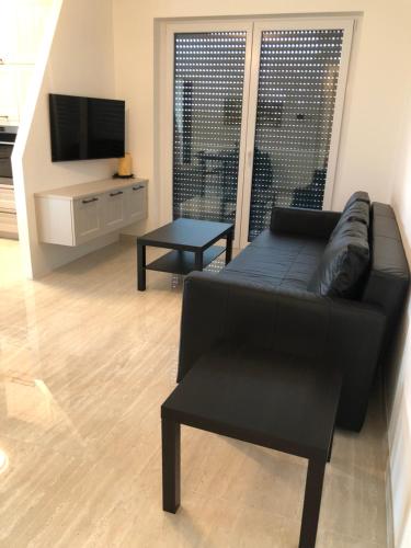 a living room with a black couch and a tv at Résidence du Golf Eselborn in Eselborn