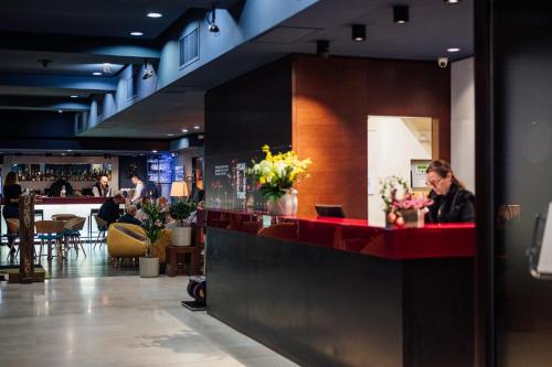 uma mulher sentada num bar num restaurante em Peakture Hotel em Bucareste