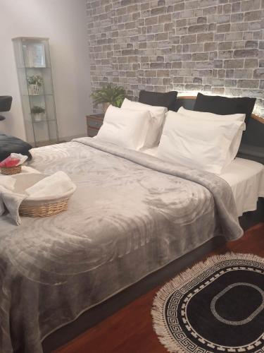 a large bed with white pillows and a brick wall at Lovely Cozy Apartment in the entrance of Nicosia in Aglantzia