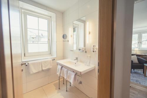 a white bathroom with a sink and a window at Hotel Kendler in Sankt Gilgen